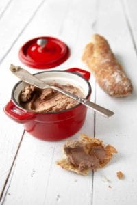 A small reck crock of easy chicken liver pate, nearby a baguette and and a hunk of bread smeared with pate