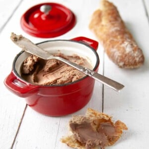 A small reck crock of easy chicken liver pate, nearby a baguette and and a hunk of bread smeared with pate