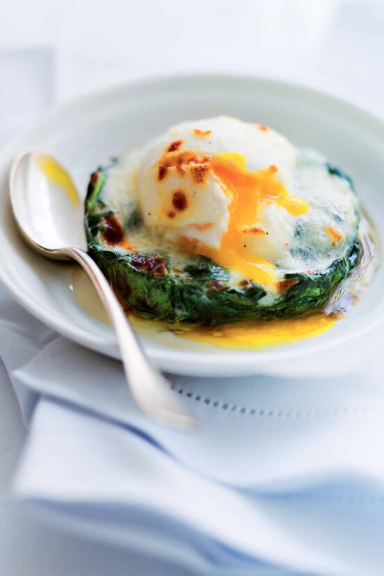 A white bowl with a easy eggs Florentine--a poached egg on top of a bed of cooked spinach