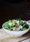 A bowl of a little gem salad--made up of little gem lettuce, radishes, shallots, walnuts, and walnut vinaigrette