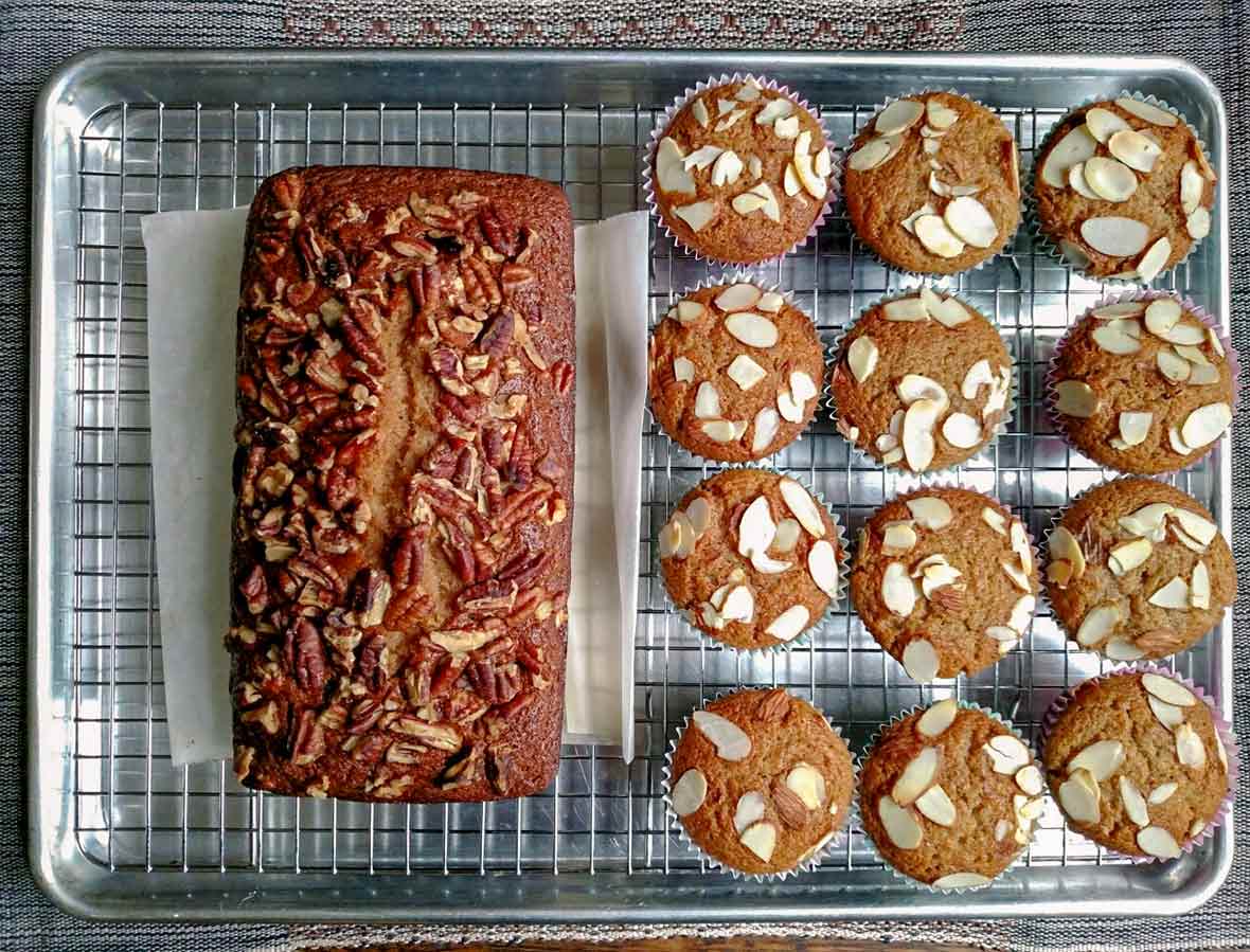 A loaf of applesauce bread and a dozen applesauce bread muffins on a wire rack in a rimmed baking sheet