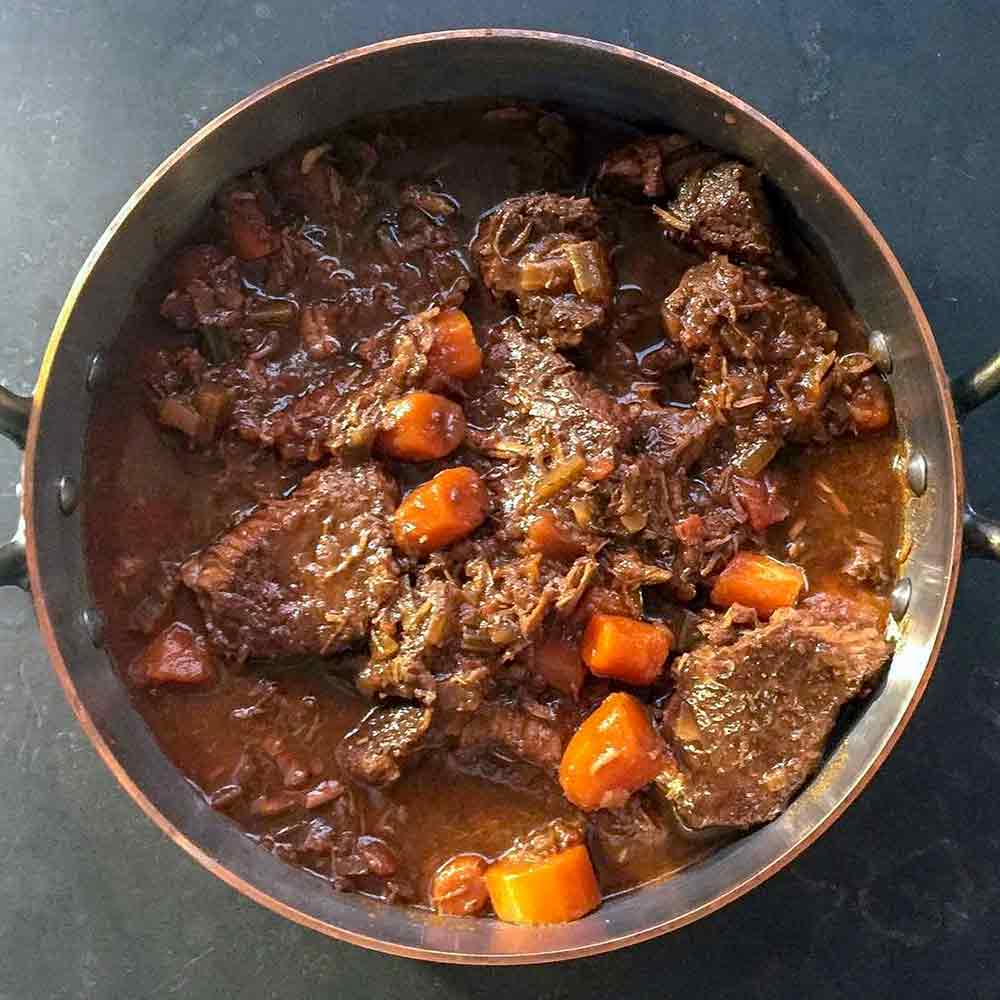 A big pot of beef daube or a classic French beef stew with chunks of beef and carrots in a wine sauce