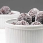Two white ramekins with a pile of sugar-coated bourbon balls