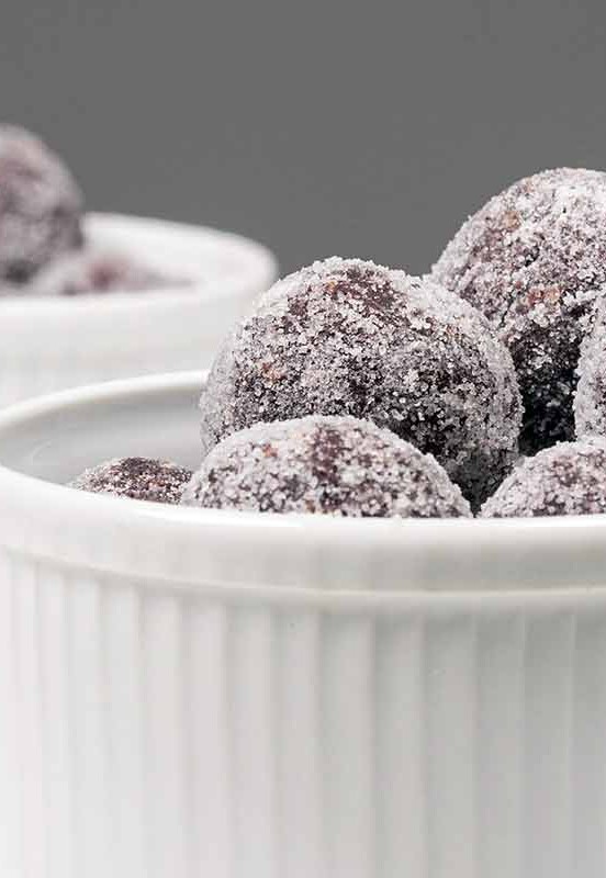 Two white ramekins with a pile of sugar-coated bourbon balls
