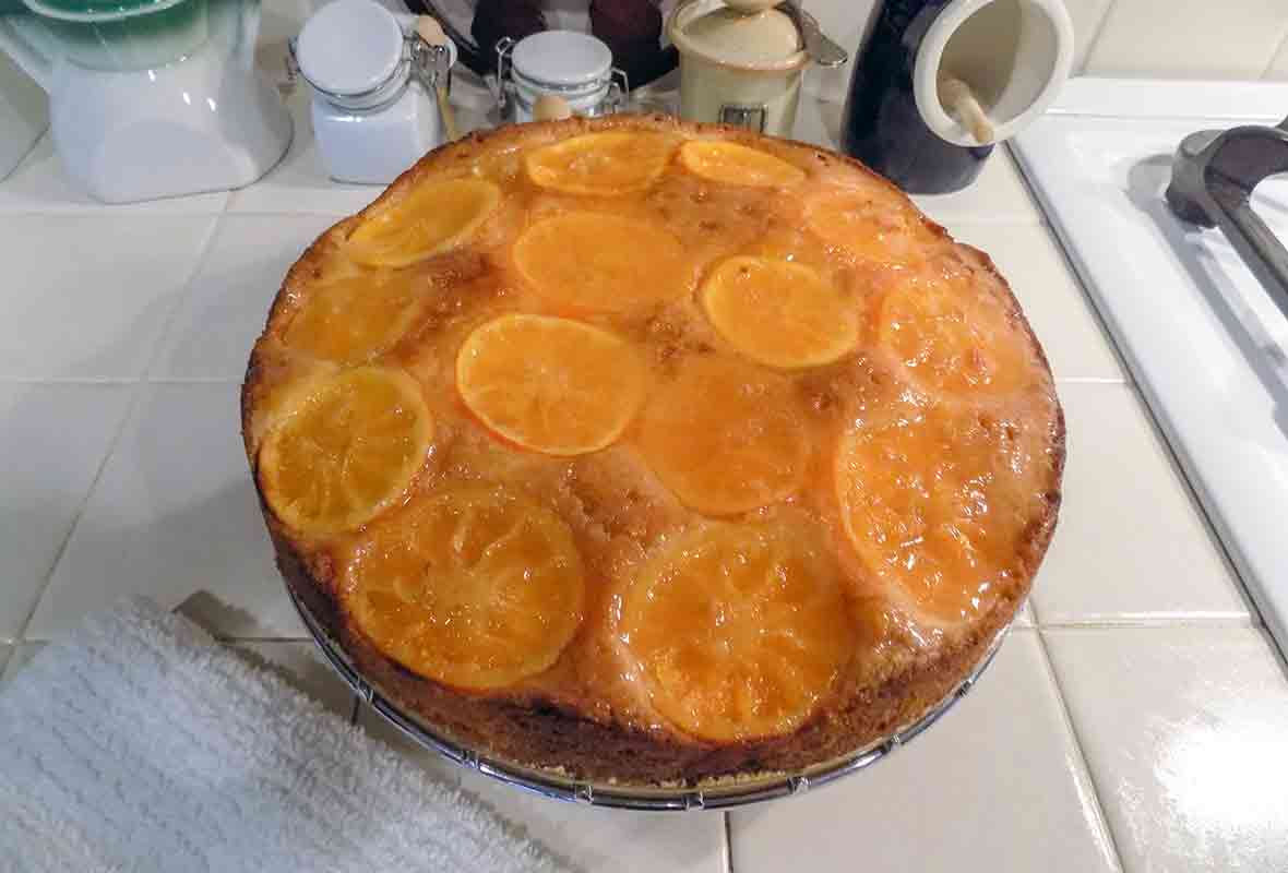 A clementine cake, topped with sliced clementines and a sweet glaze