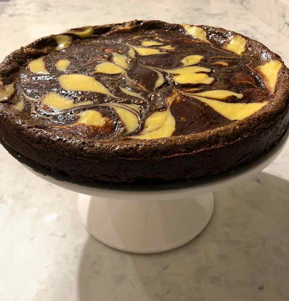 A flourless chocolate-vanilla swirl marble cake--on a white cake stand