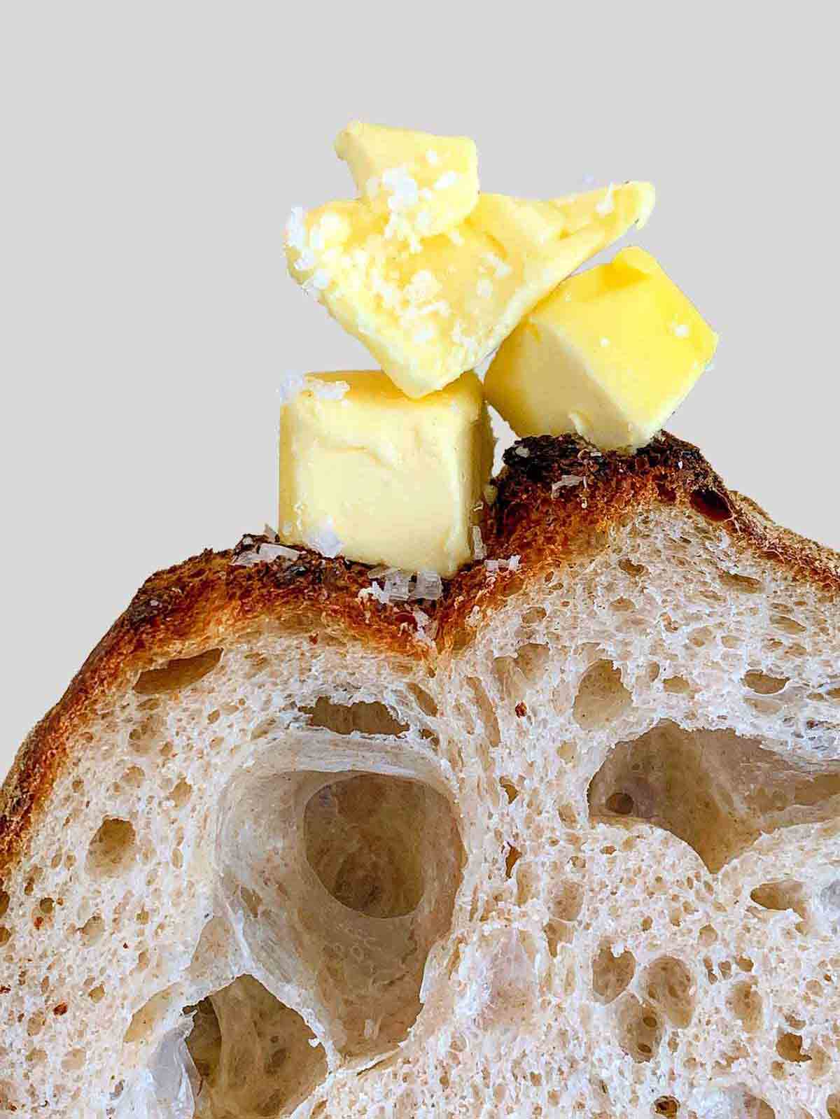 En bit av Jim Laheys no-knead bröd med tre bitar smör och ett stänk salt på toppen.