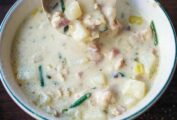 A bowl of creamy New England clam chowder with clams, potatoes, leeks, shallots, cream, and chives