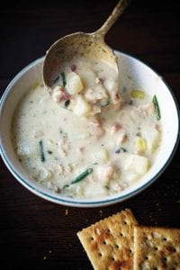 A bowl of creamy New England clam chowder with clams, potatoes, leeks, shallots, cream, and chives
