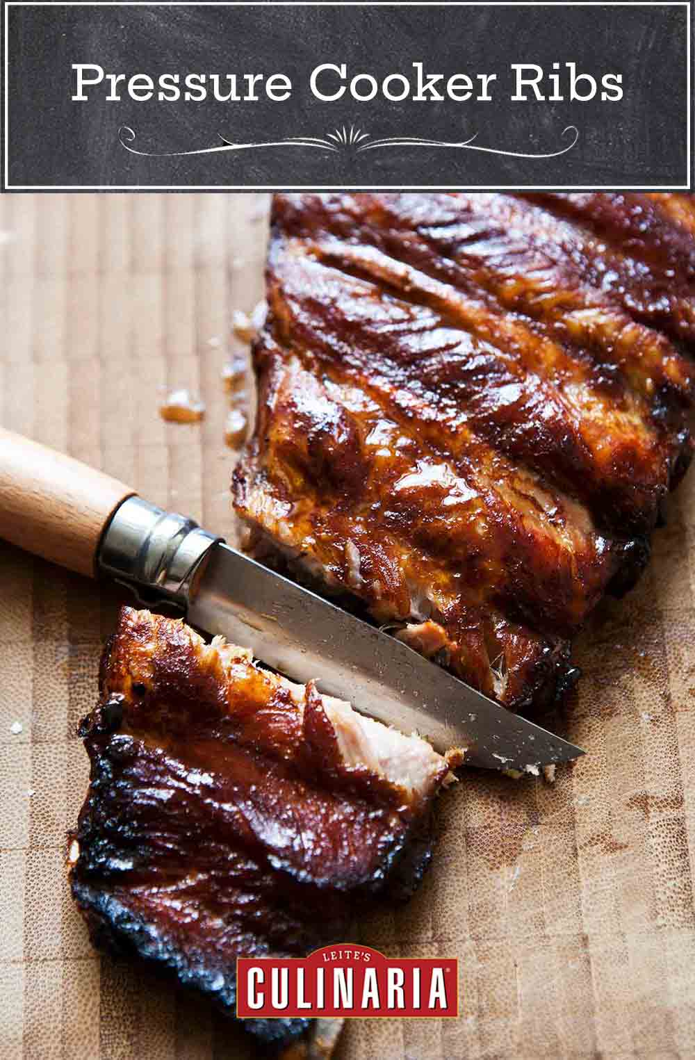 A slab of glazed pressure cooker ribs with a knife cutting between two ribs