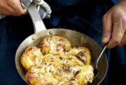 A man with a skillet of Portuguese punched potatoes, caramelized onions, cheese, called batatas a murro in Portuguese