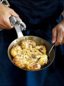 A man with a skillet of Portuguese punched potatoes, caramelized onions, cheese, called batatas a murro in Portuguese