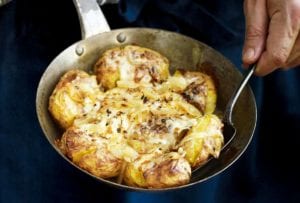 A man with a skillet of Portuguese punched potatoes, caramelized onions, cheese, called batatas a murro in Portuguese