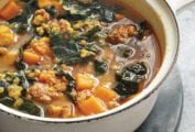 Bowl of red lentil soup with kale and chorizo, sweet potatoes, and onions