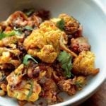 A bowl of roasted curried cauliflower mixed with onions and topped with cilantro.