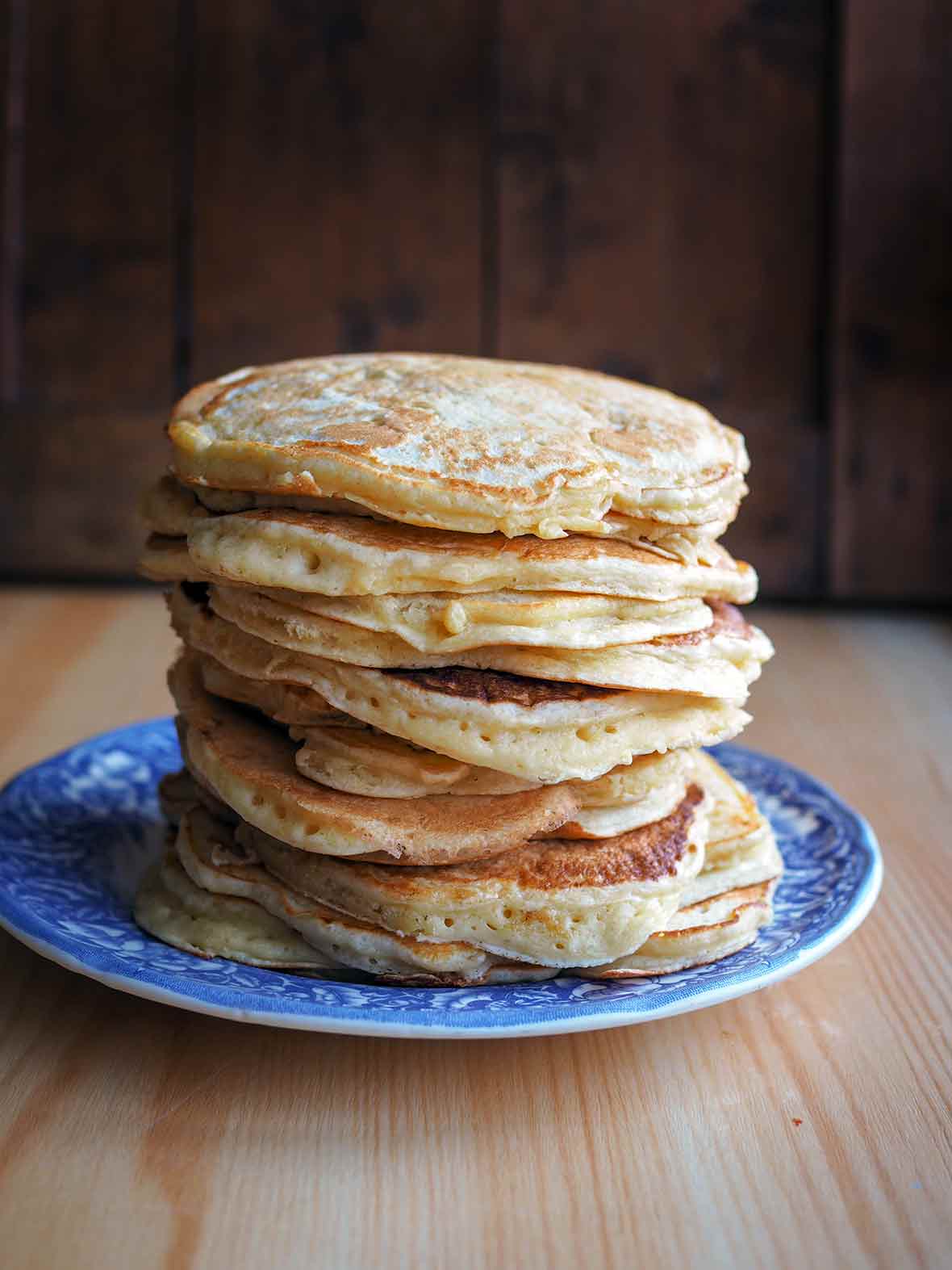 A blue plate piled with a stack of griddle cakes.