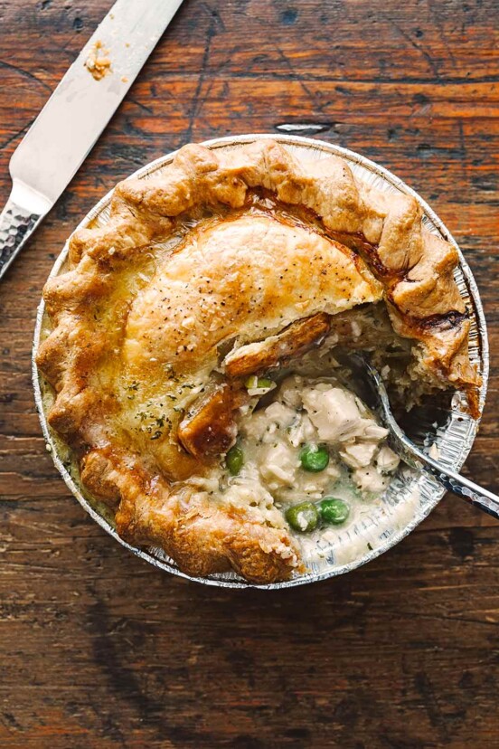 A mini homemade chicken pot pie with a flaky crust, chunks of white meat chicken, and peas