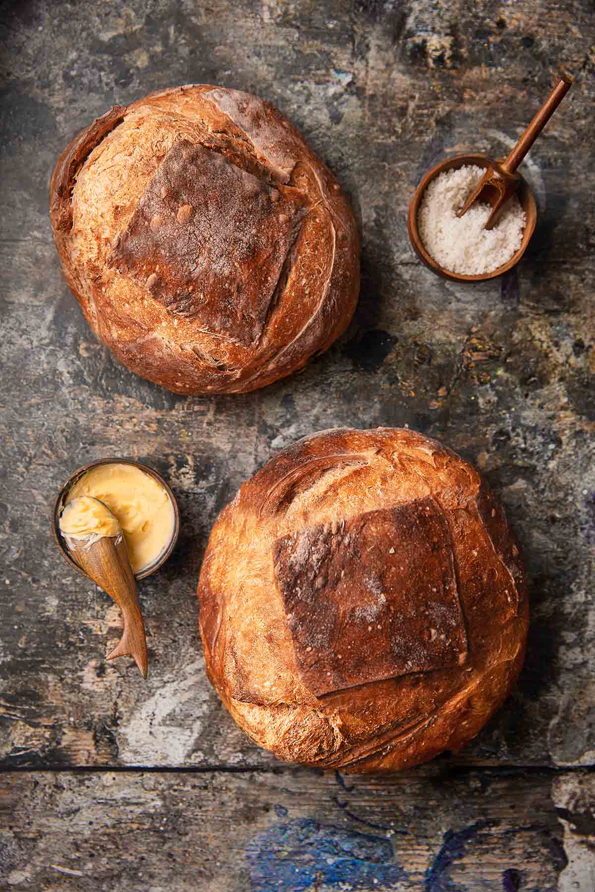 Two loaves of no-knead artisan bread and a dish of butter nearby.