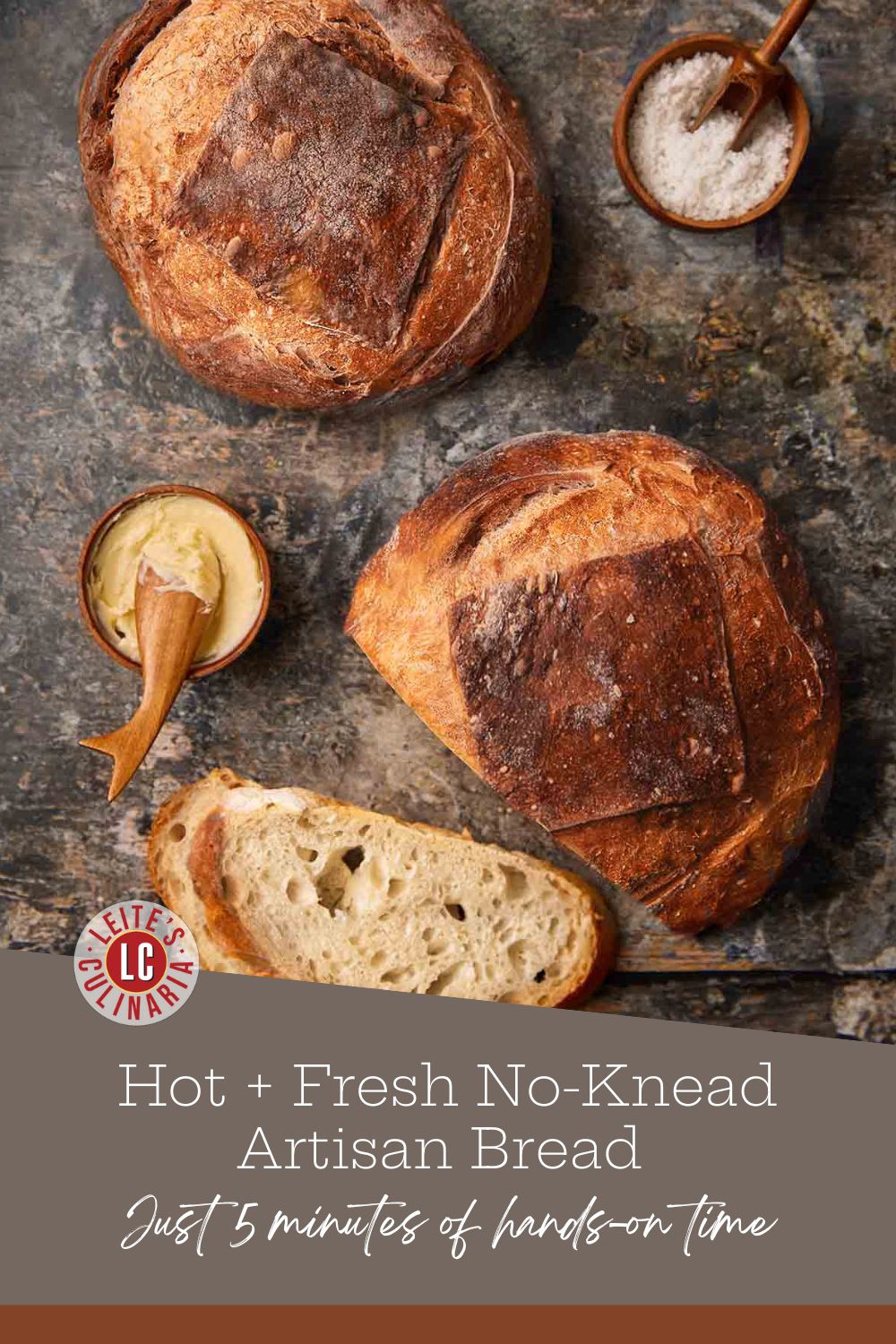 A sliced loaf and an uncut loaf of no-knead artisan bread on a wooden board next to a small bowl of butter and a salt cellar.