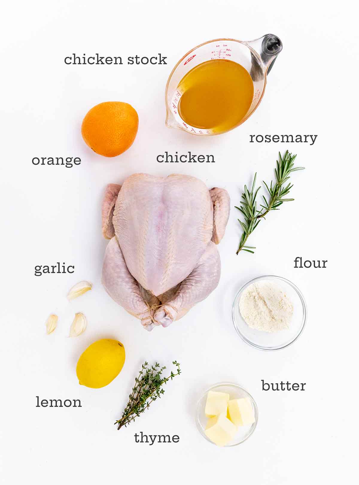 A chicken, orange, lemon, stock, and herbs on a white background.