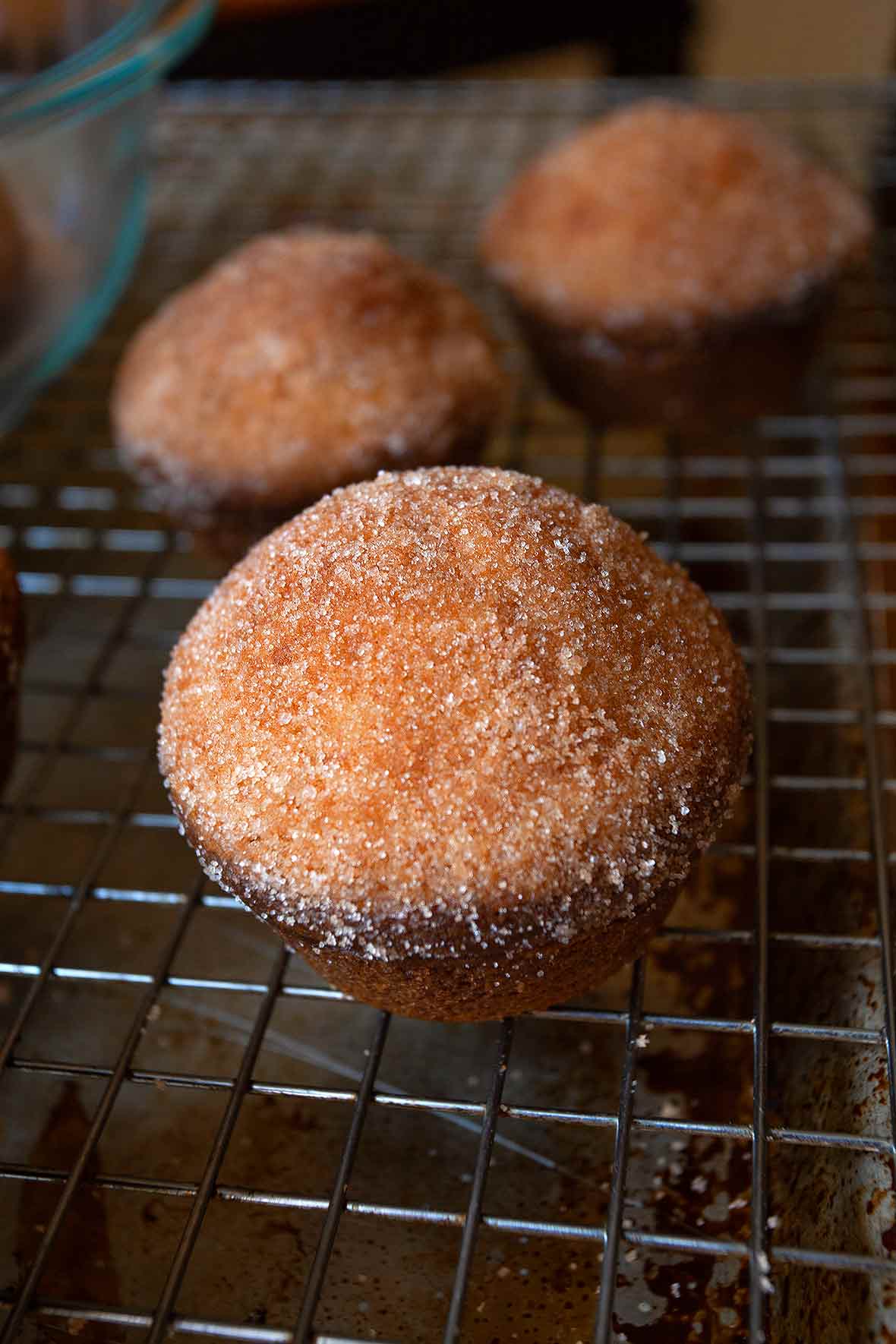 Three dirt bombs cooling on a wire rack, and one in a bowl of cinnamon sugar