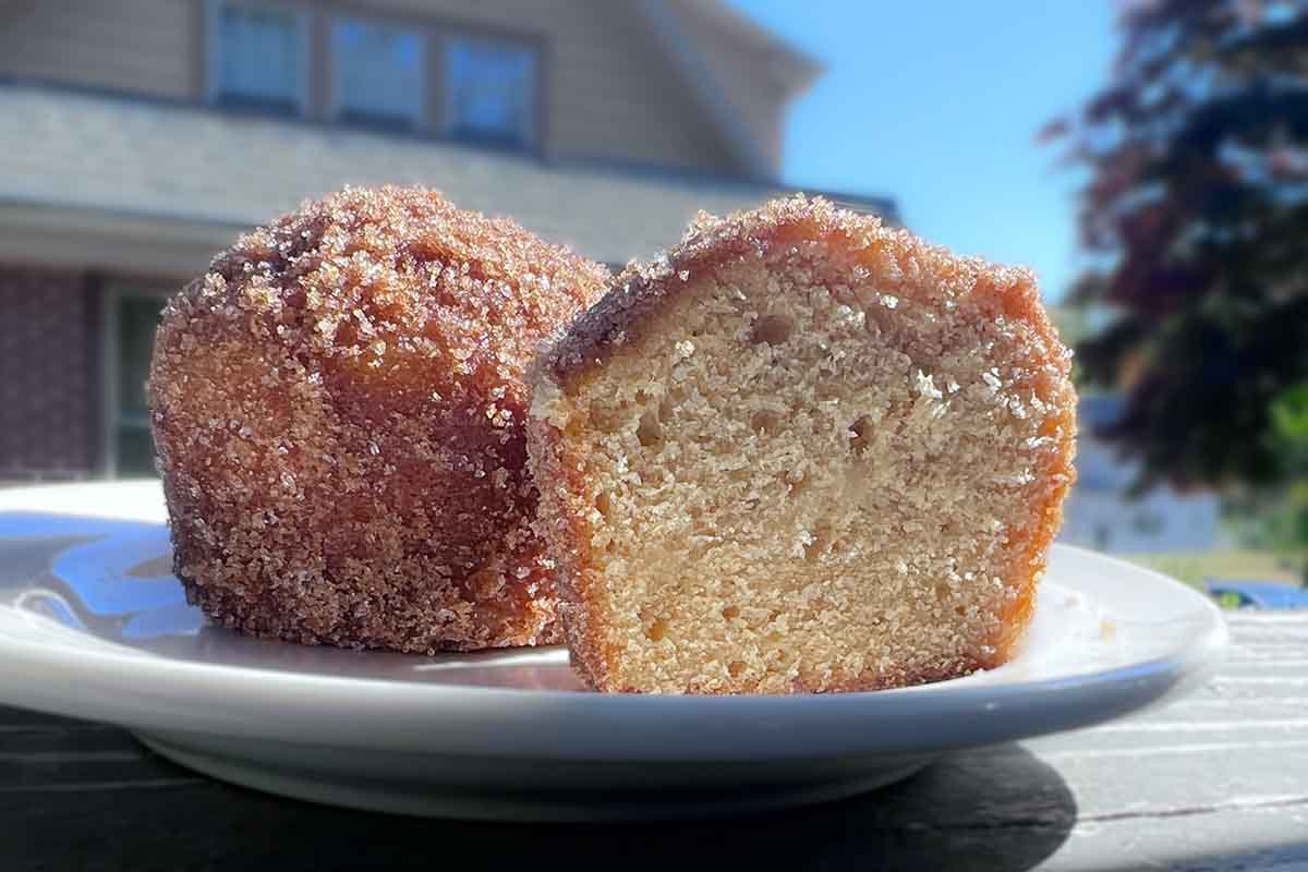 A dirt bomb muffin cut in half on a white plate in the bright sunshine.