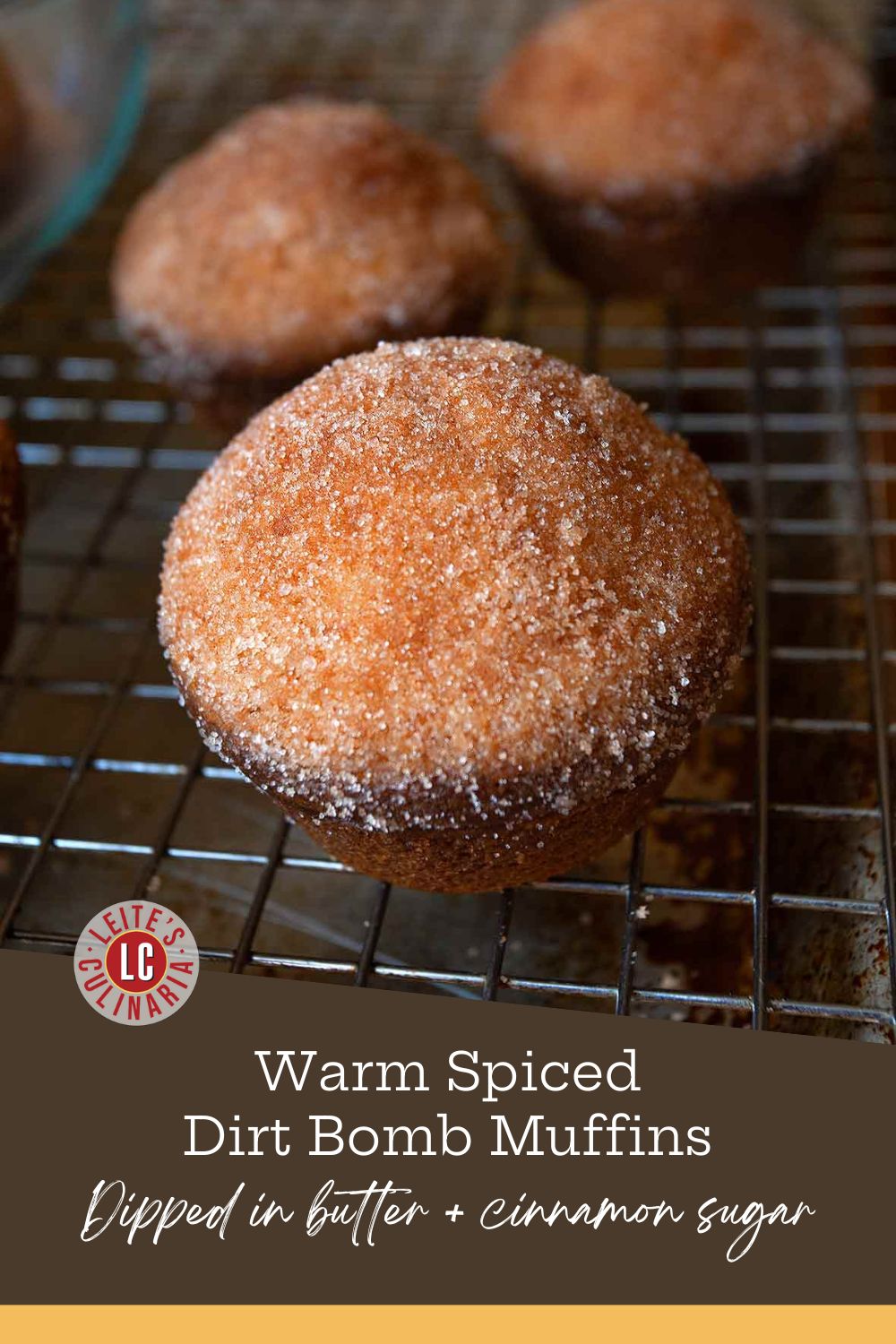 A close-up of a single, round dirt bomb muffin coated in coarse cinnamon sugar on a wire rack.