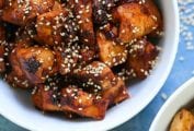 A white bowl filled with spicy Korean chicken and sprinkled with sesame seeds.