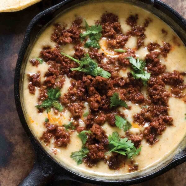 A cast-iron skilled filled with choriqueso, a cheese dip topped with queso.