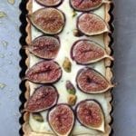 A cooked rectangular fig tart with goat cheese and pistachios in a tart pan