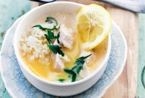 A white and blue bowl filled with healthy avgolemono made with fish, rice, and lemon