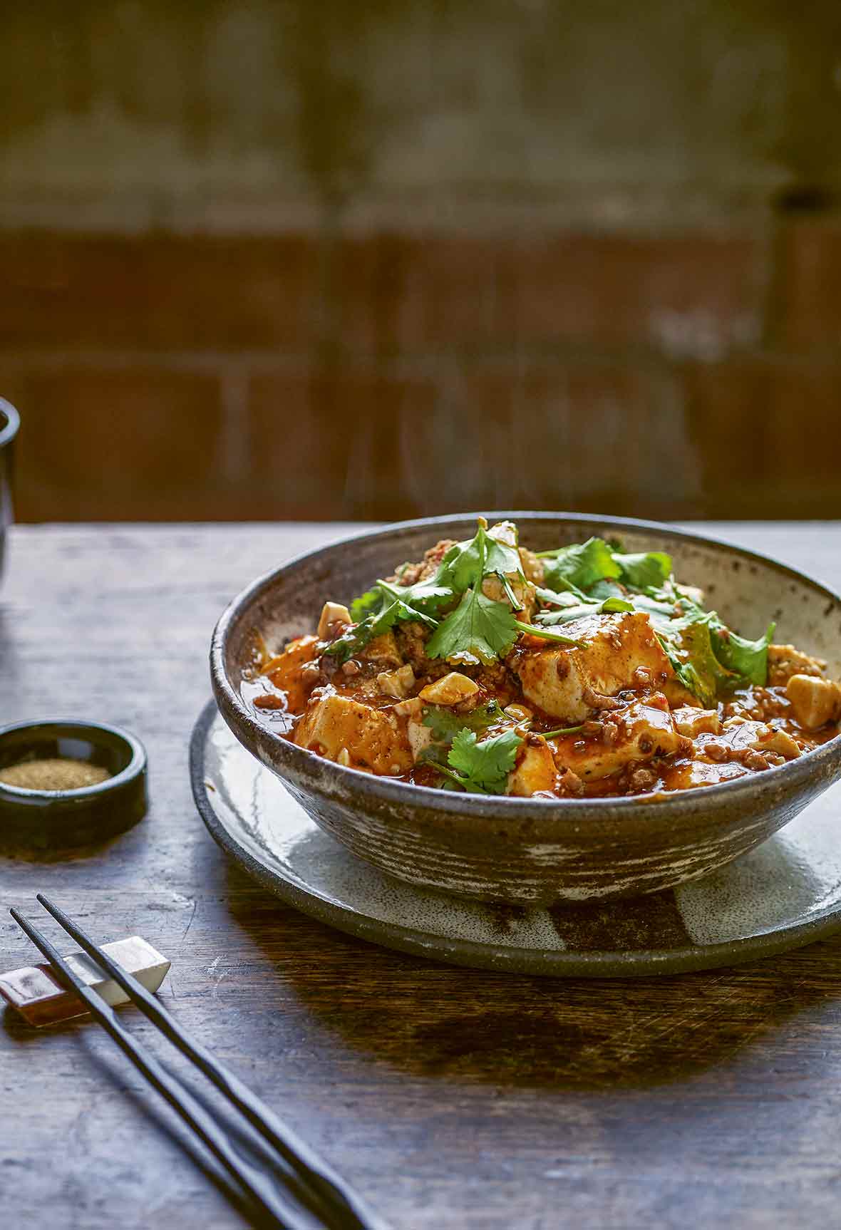 A bowl filled with Sichuan tofu noodles and a pair of chopsticks resting beside