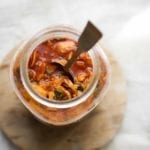 A jar of the best kimchi with a spoon standing up inside it