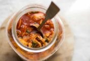 A jar of the best kimchi with a spoon standing up inside it