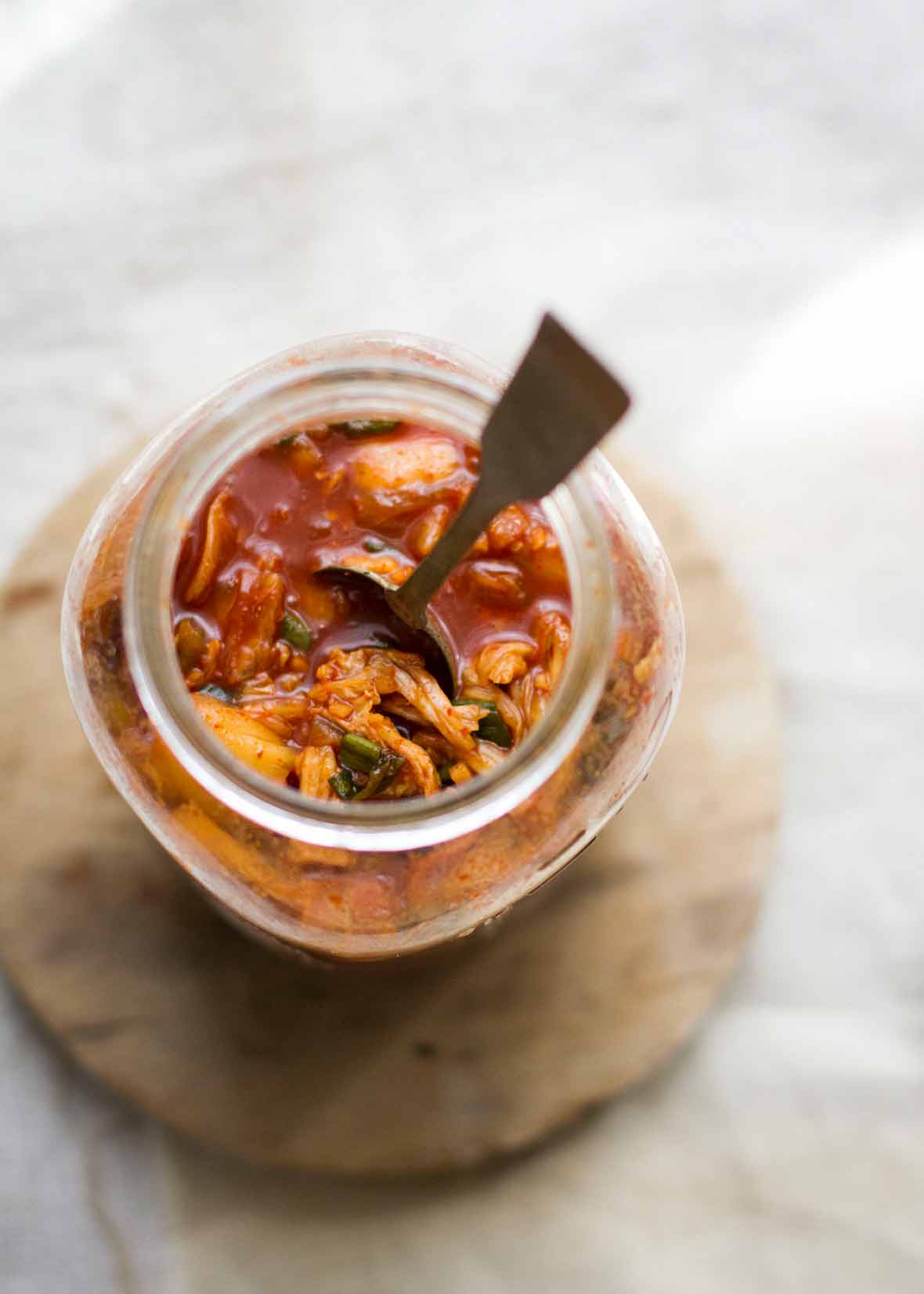 A jar of the best kimchi with a spoon standing up inside it