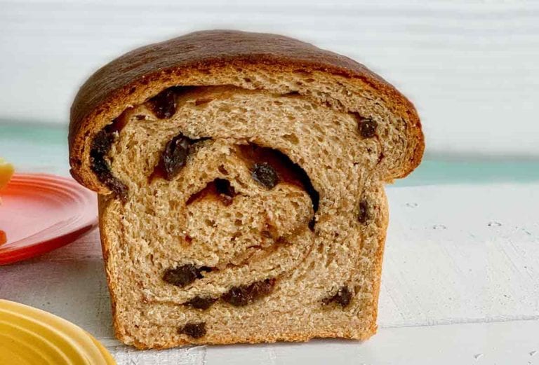 A loaf of cinnamon raisin swirl bread cut in half so the swirl is visible.