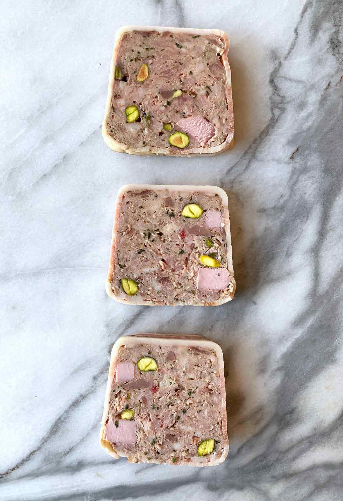 Three slices of pate de campagne on a marble surface