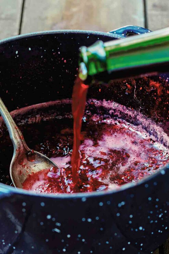 A pot of raspberry jam with framboise being added to it.