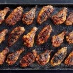 A rimmed baking sheet with 18 grilled chicken wings with maple bourbon sauce.