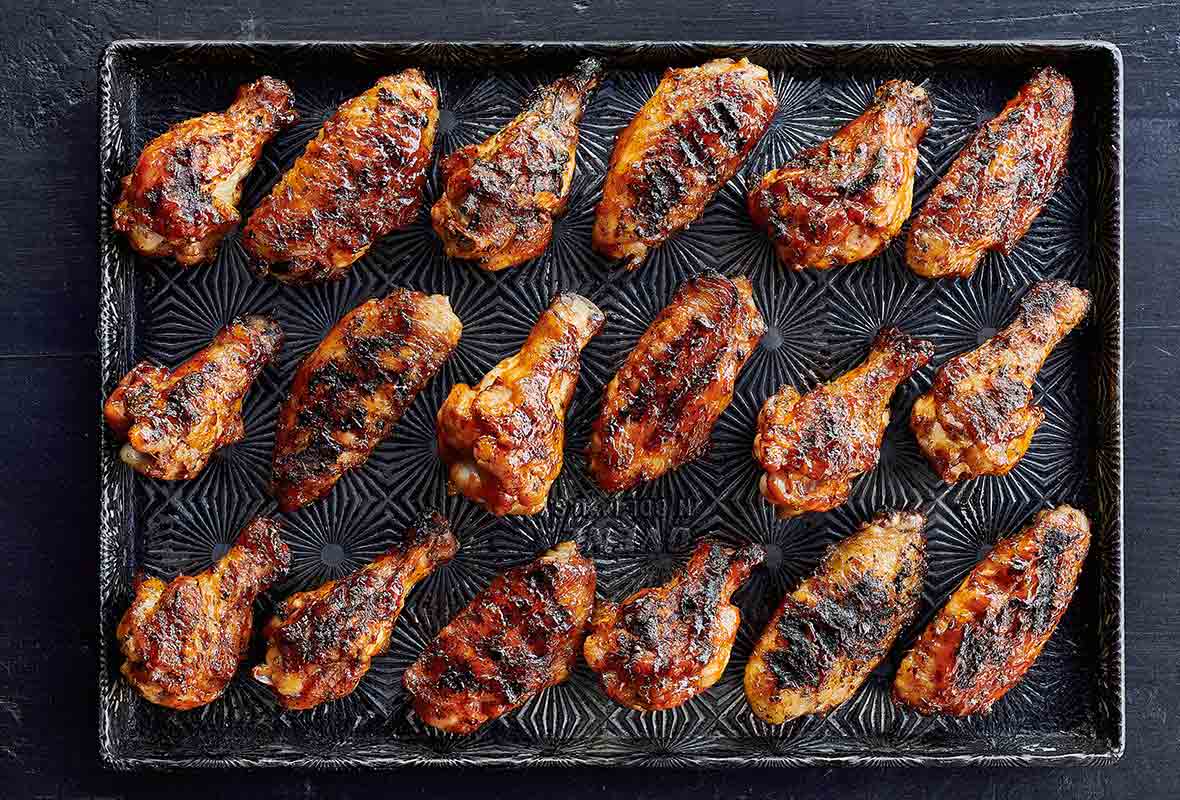 A rimmed baking sheet with 18 grilled chicken wings with maple bourbon sauce.
