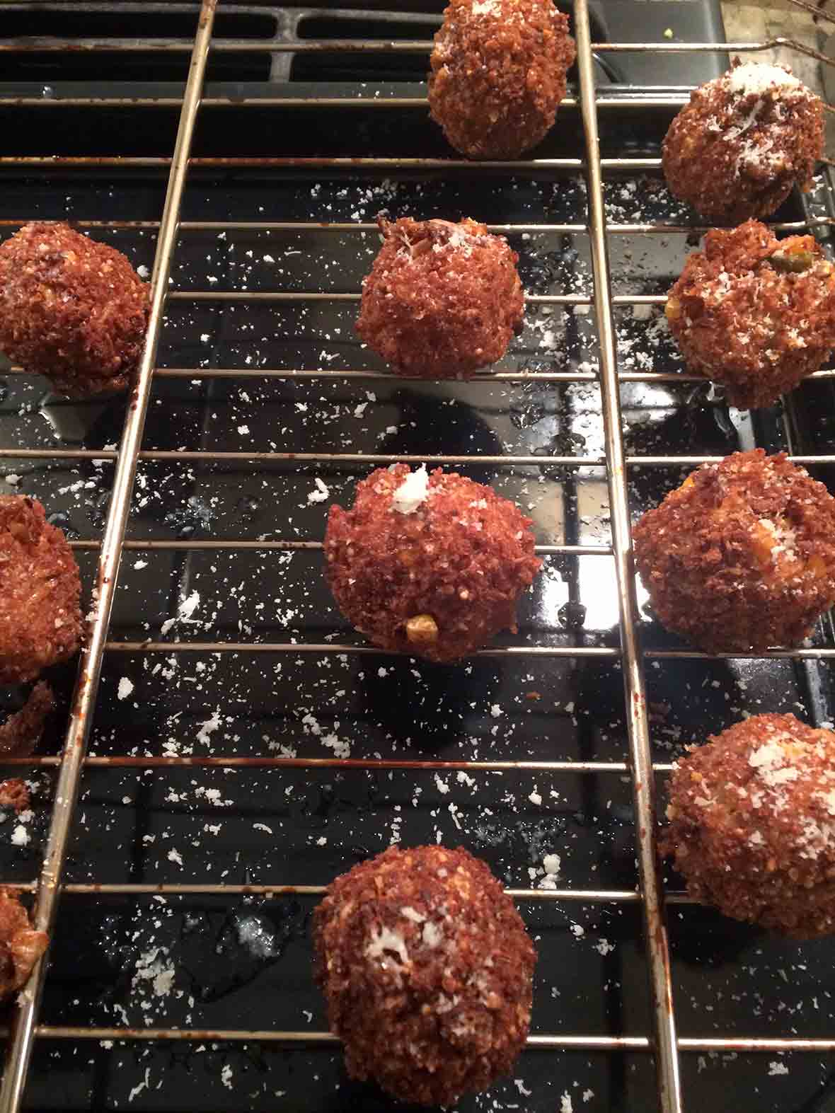 Ten deep-fried kimchi arancini on a wire cooling rack.