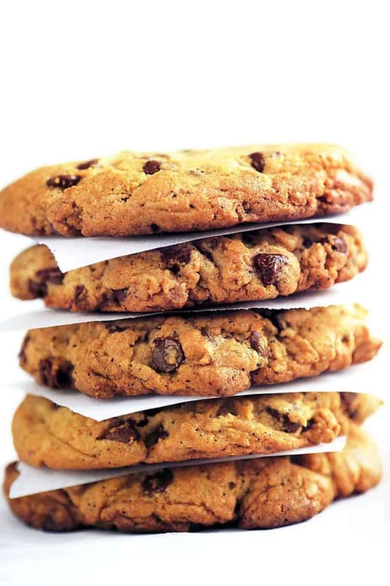 A stack of Neiman Marcus chocolate chip cookies separated by pieces of parchment.