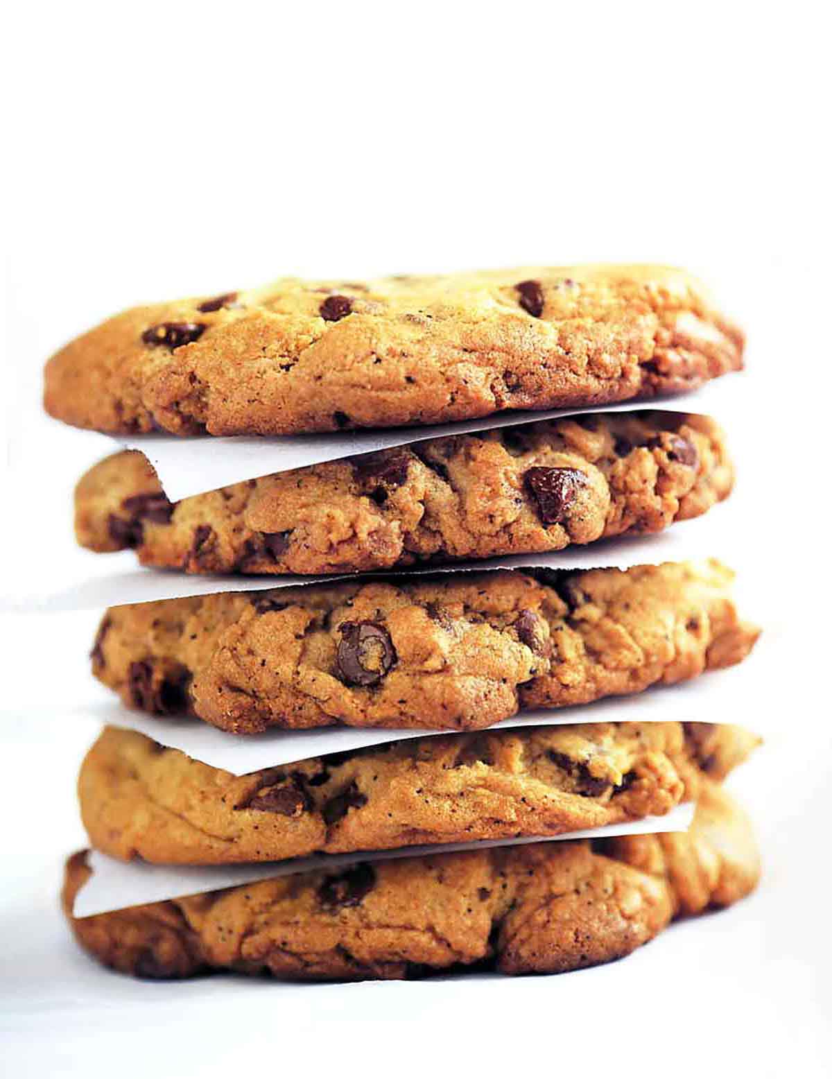 A stack of Neiman Marcus chocolate chip cookies separated by pieces of parchment.