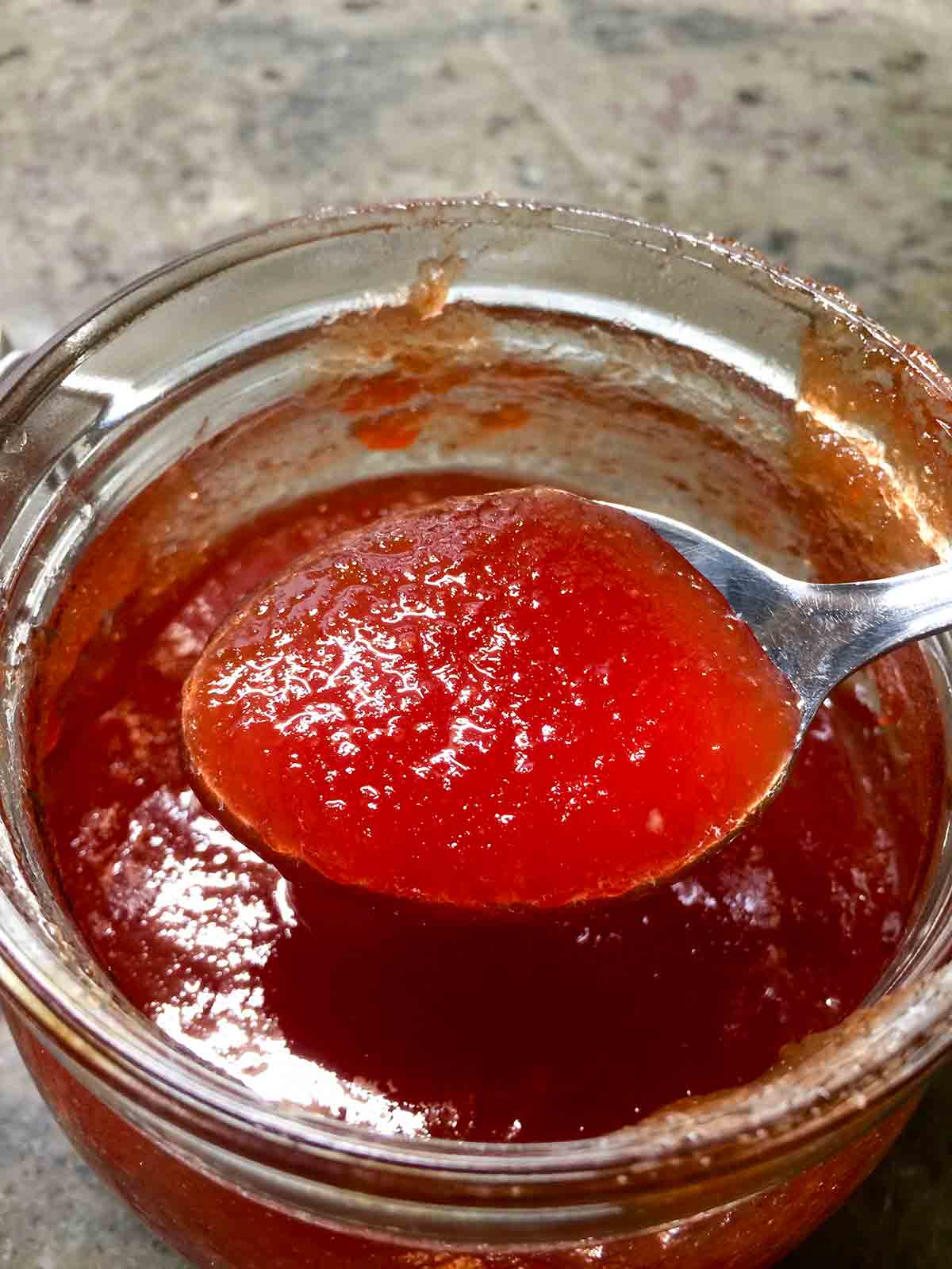 A jar of Portuguese tomato jelly with a filled spoon above it.