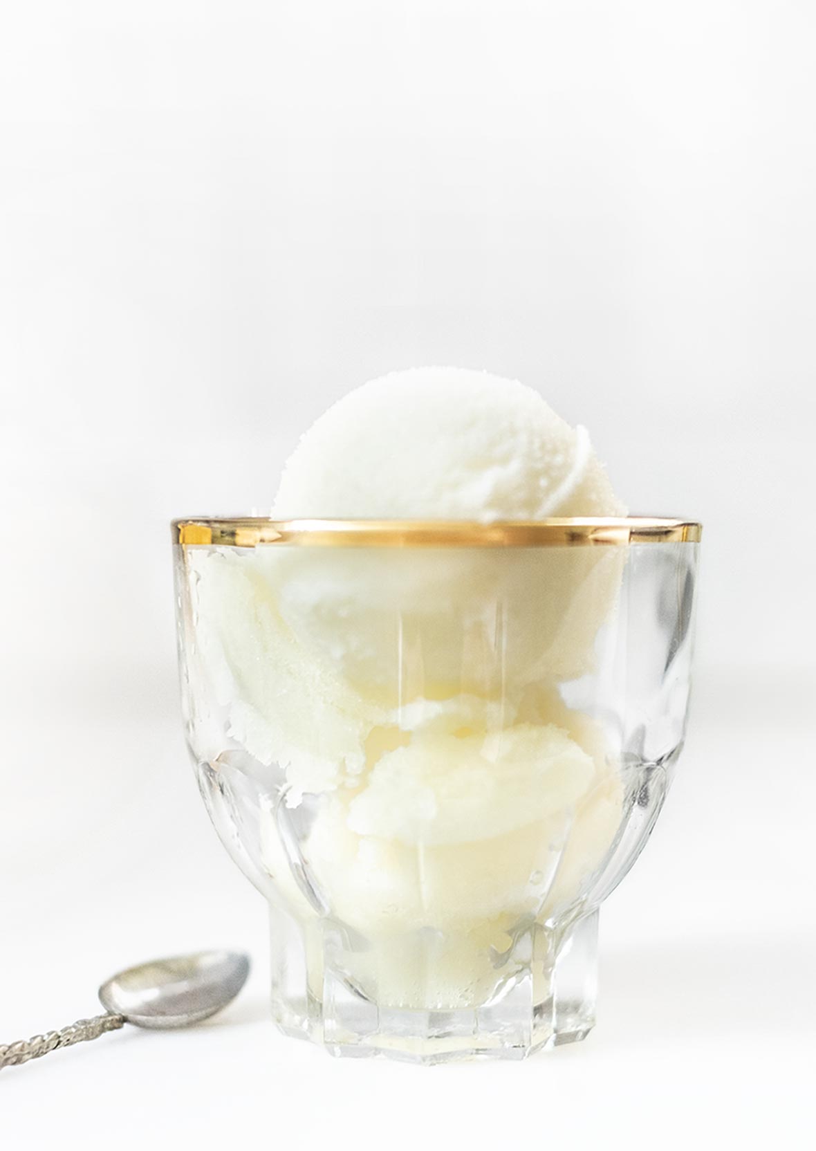 A small glass serving bowl with two scoops of tart lemon sorbet.