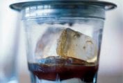 A glass of Vietnamese iced coffee, made with layers of sweetened condensed milk, coffee, and ice cubes with a coffee drip over it.