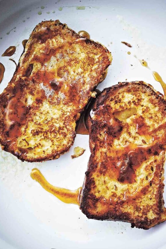 Two slices of French toast, fried until golden and drizzled with maple syrup.