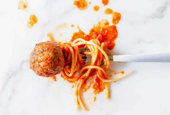 A single eggplant meatball on a fork with spaghetti and tomato sauce.