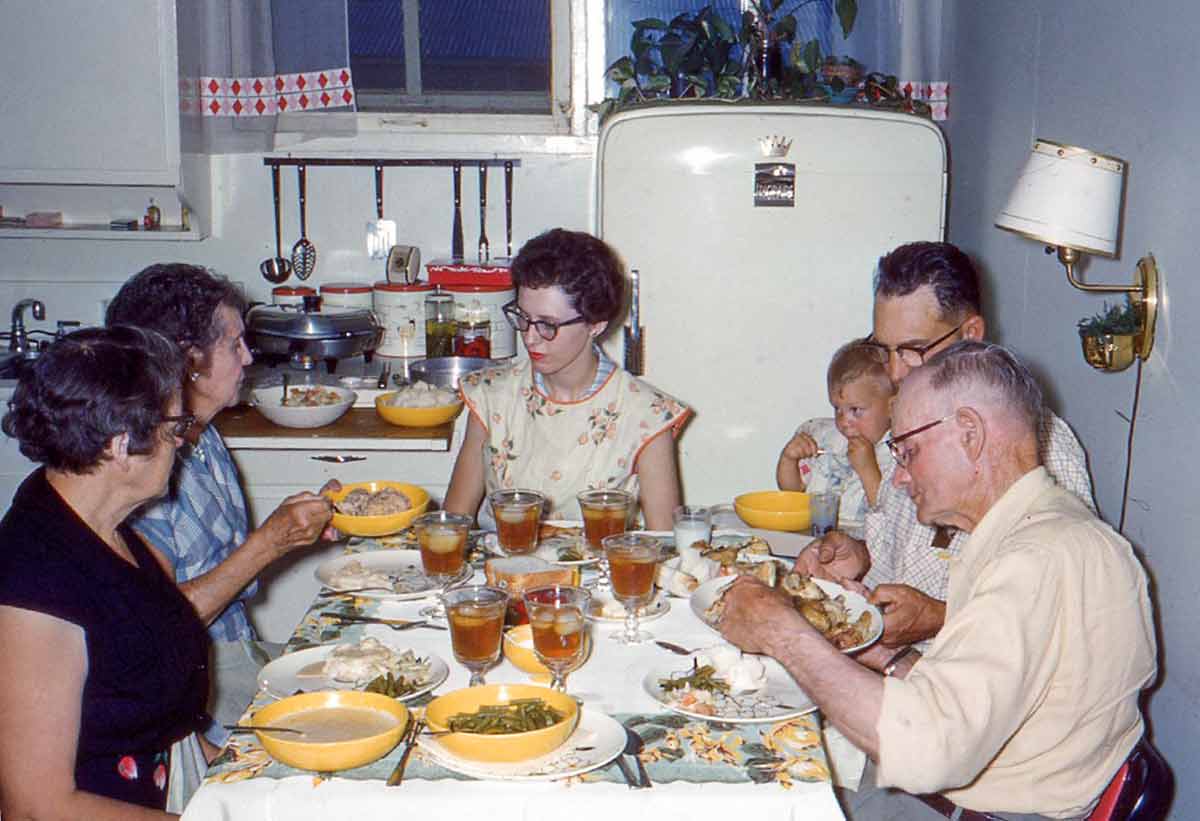 A family at dinner in a kitchen, from the 1960s