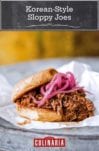 Korean-style sloppy joes made with shredded beef, topped with pickled red onion on a hamburger bun resting on a piece of parchment.